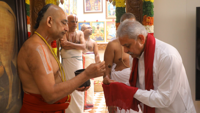Devotee receiving sacred Theertham in traditional Vaishnava manner